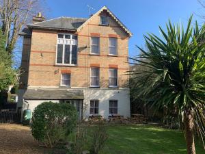 ein altes Backsteinhaus mit einer Palme davor in der Unterkunft The Bournemouth Villa by the Sea, sleeps 26 in Bournemouth