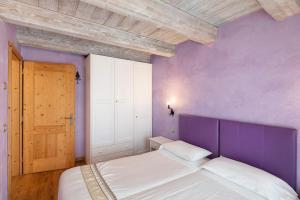 een paarse slaapkamer met een bed en een houten deur bij Chalet Picchio Bilocale in Livigno