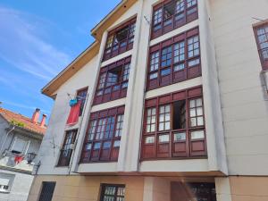 un edificio con ventanas rojas y blancas en APARTAMENTO BARLOVENTO en San Vicente de la Barquera