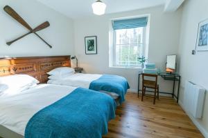 two beds in a bedroom with a desk and a window at Coron in Aberffraw