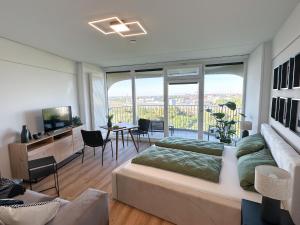 een woonkamer met 2 bedden en een televisie bij Helles Apartment mit tollem Blick über Augsburg in Augsburg