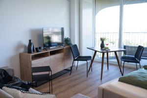 a living room with a tv and a table and chairs at Helles Apartment mit tollem Blick über Augsburg in Augsburg