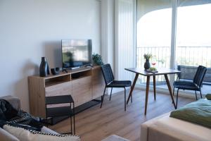 een woonkamer met een tv en een tafel en stoelen bij Helles Apartment mit tollem Blick über Augsburg in Augsburg
