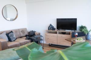 a living room with a couch and a flat screen tv at Helles Apartment mit tollem Blick über Augsburg in Augsburg +12 photos