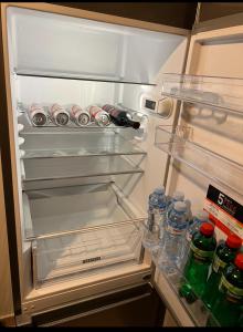 - un réfrigérateur ouvert rempli de canettes de soda et de bouteilles d'eau dans l'établissement Stella LUX Apartment, à Nova Pazova