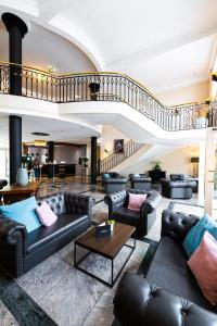 a living room with leather couches and a staircase at Bernstein Schlosshotel Ballenstedt in Ballenstedt