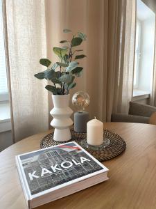 a book on a table with a vase and a candle at Kaunis huoneisto Turun Kakolassa in Turku