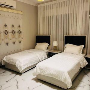 Luxury 4-bedrooms apartment في العقبة: سريرين في غرفة نوم مع ملاءات ووسائد بيضاء
