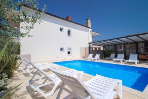 a swimming pool with white chairs and a house at Apartments Villa Rivarella in Novigrad Istria