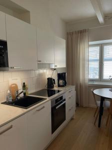 a kitchen with white cabinets and a sink and a table at Kaunis huoneisto Turun Kakolassa in Turku