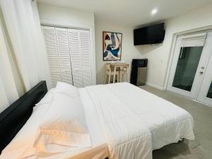 um quarto com uma cama branca e uma televisão em Nuvole Guest Suite em Miami
