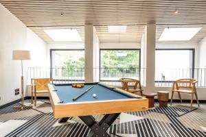 una mesa de billar en una habitación con ventanas en Hôtel Parc du Landreau, en Les Herbiers