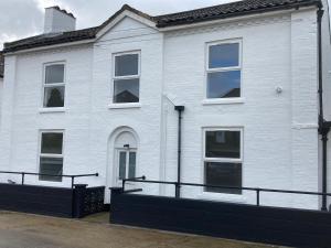 a white house with a black fence in front of it at The Whitehouse in Norwich