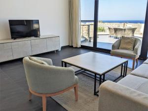 ein Wohnzimmer mit einem TV, einem Tisch und Stühlen in der Unterkunft Sea & Golf Views 2BR Villa with Free Beach & Pool Access in Hurghada