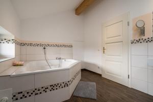a white bathroom with a tub and a white door at Ferienhaus Landurlaub mit Kamin in Schwarz +49 photos