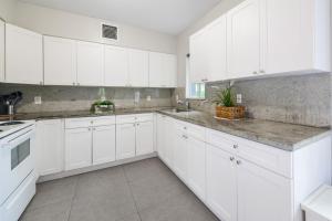 uma cozinha branca com armários brancos e um lavatório em Awesome Duplex on the East side of Miami em Miami