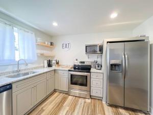 a kitchen with stainless steel appliances and wooden floors at 2BR Cedar Lane Road Retreat at Swamp Rabbit Trail! in Greenville