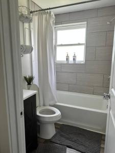 a bathroom with a toilet and a tub and a window at 2BR Cedar Lane Road Retreat at Swamp Rabbit Trail! in Greenville
