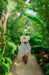 a person wearing a hat walking through a garden at Le Muuch Hotel Boutique in Valladolid