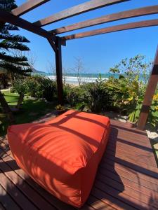 an orange bean bag chair on a deck with the beach at Hospedaria Sol da Manhã in Bombinhas