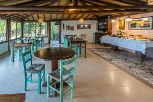 a restaurant with tables and chairs in a room at Pousada Watu Kerere in Praia do Rosa