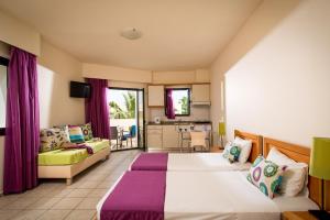 a hotel room with two beds and a couch at Kristalli Hotel Apartments in Malia