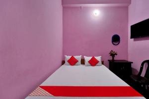 a bedroom with pink walls and a bed with red pillows at SPOT ON Hotel Gajraj in Patna