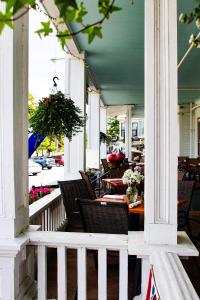 eine Veranda mit Stühlen und Tischen mit Blumen darauf in der Unterkunft Fullerton Inn & Restaurant in Chester