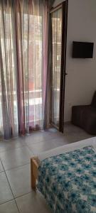 a bedroom with a bed and a couch and windows at Avli Apartments in Pyrgadikia