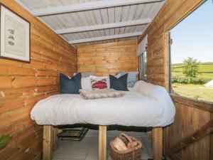 a bed in a log cabin with a window at The Snug in Dulverton
