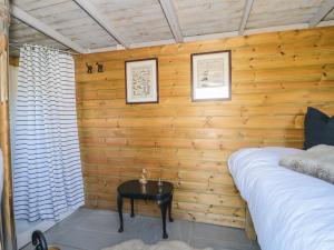 a bedroom with wooden walls and a bed and a table at The Snug in Dulverton +5 photos