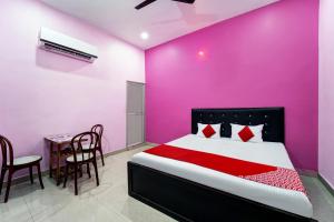 a bedroom with a bed and a table and chairs at OYO Flagship Raj Munmun Hotel in Dhanbād