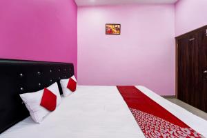 1 dormitorio con 1 cama con almohadas rojas y blancas en OYO Flagship Raj Munmun Hotel, en Dhanbād
