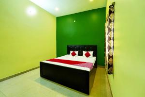 1 dormitorio verde con 1 cama con sábanas rojas en OYO Flagship Raj Munmun Hotel, en Dhanbād