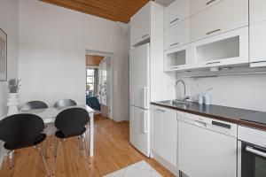 ヘルシンキにあるWeHost Penthouse Studio with Sauna and Balcony @Meritullinkatu 13 Aの白いキャビネットと黒い椅子付きのキッチン