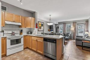 a kitchen with white appliances and a living room at Rocky Mountain Getaway with Outdoor Heated Pool, 3 Hot Tubs, Gym, BBQ, Garage & 24 hour Reception near Banff in Canmore