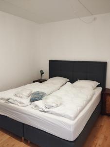 łóżko z białą pościelą i czarnym zagłówkiem w obiekcie (Id 039) Rørkjærsgade 12 dor 209 w mieście Esbjerg