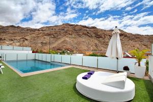une terrasse avec une piscine, un parasol et de la pelouse dans l'établissement Villa Tauro 31, à Mogán