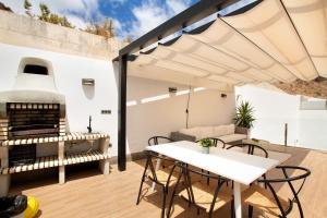 een patio met een tafel en stoelen en een grill bij Villa Tauro 31 in Mogán