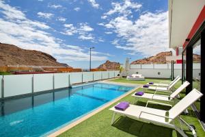 a pool on the roof of a house with lounge chairs at Villa Tauro 31 in Mogán