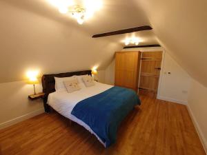 ein Schlafzimmer mit einem Bett mit einer blauen Decke und 2 Lampen in der Unterkunft The Carthorse Barn, North End Farm, Ashton Keynes, in South Cerney