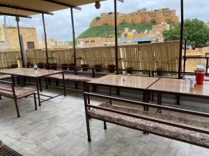 eine Reihe von Tischen und Bänken auf einem Dach mit einem Schloss in der Unterkunft Hotel Hashim in Jaisalmer