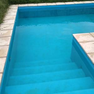 a blue swimming pool with stairs in a yard at Cabañas Plottier-Neuquén in Plottier