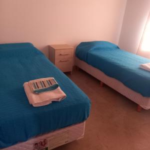 1 dormitorio con 2 camas y sábanas azules en Cabañas Plottier-Neuquén en Plottier