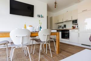 een keuken met witte stoelen en een houten tafel bij DER STÖRTEBEKER - "Apartment Born" Apartments hinter den Dünen in Dierhagen