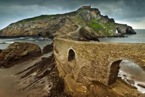 un puente en una playa con una isla en el agua en CASCO VIEJO, en Bermeo