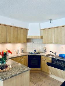 a kitchen with wooden cabinets and a black dishwasher at Haus Alpina - CharmingStay in Flumserberg