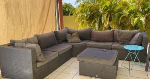 eine Terrasse mit einem Sofa, einem Tisch und Palmen in der Unterkunft Finisterre Curaçao in Sabana Westpunt
