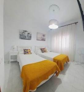 two beds in a white room with yellow sheets at Apartamentos Los Volcanes in Fuencaliente de la Palma