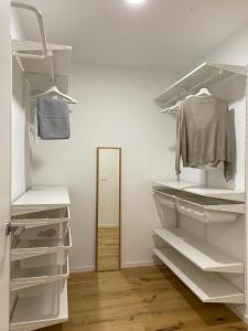 Armario blanco con estanterías blancas y espejo en Apartamento HALO VIGO, en Vigo